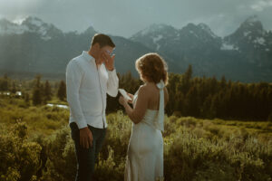 The most gorgeous rain filled golden back drop in Jackson Hole while they say their vows are you kidding me? Carlin + Andrews Grand Teton Elopement in the wildflowers.