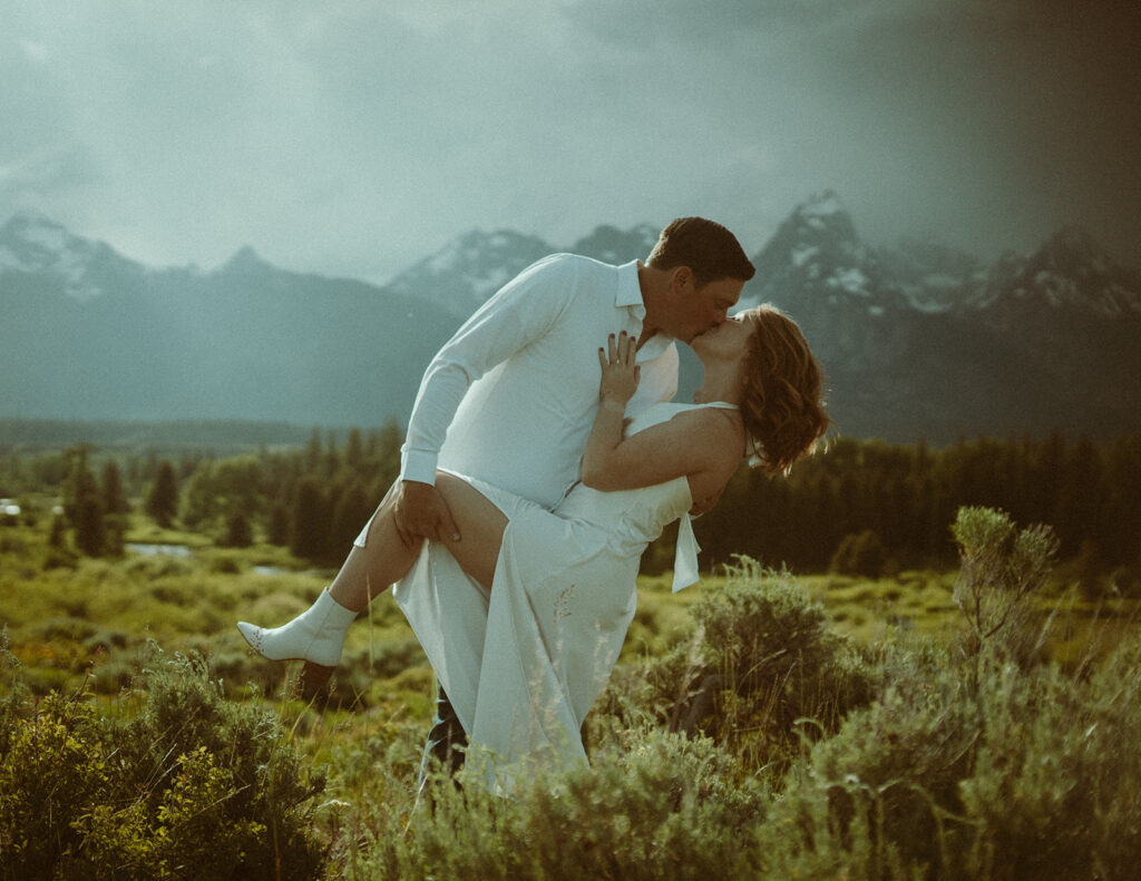 The most gorgeous rain filled golden back drop in Jackson Hole while they say their vows are you kidding me? Carlin + Andrews Grand Teton Elopement in the wildflowers.