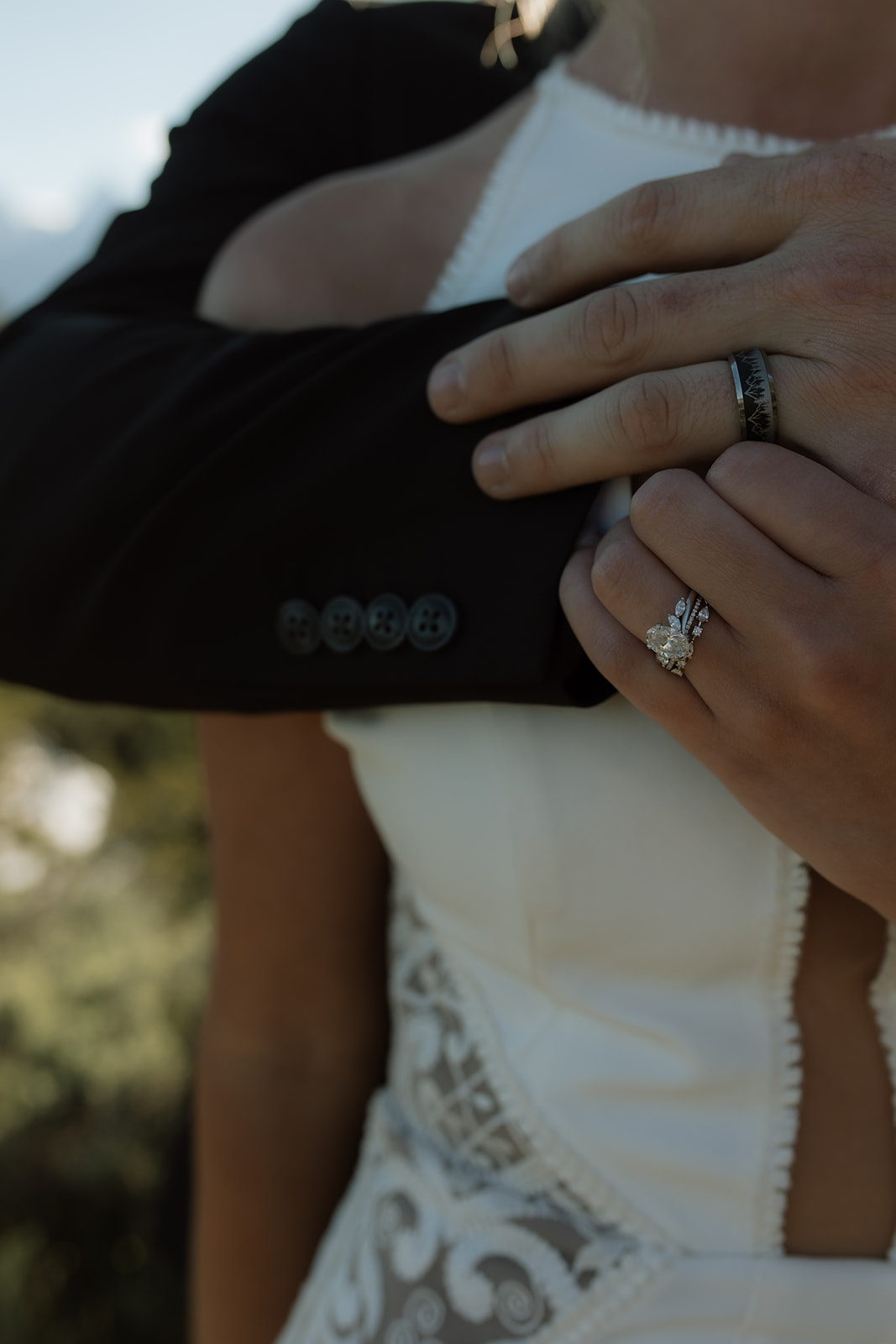 A person in a white dress and another person in a black suit are dancing outdoors on a dirt path, surrounded by trees and mountains in the background for their elopement at jackson hole