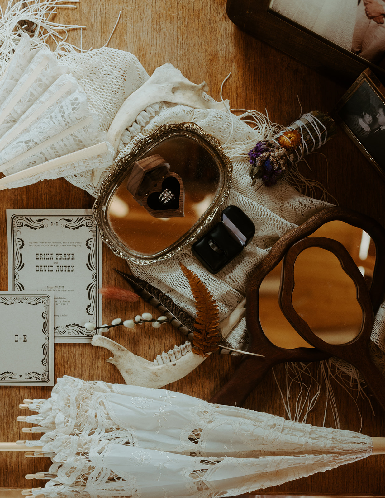 A collection of ornate mirrors, a closed umbrella, tickets, a small black box, and decorative items arranged on a wooden surface.