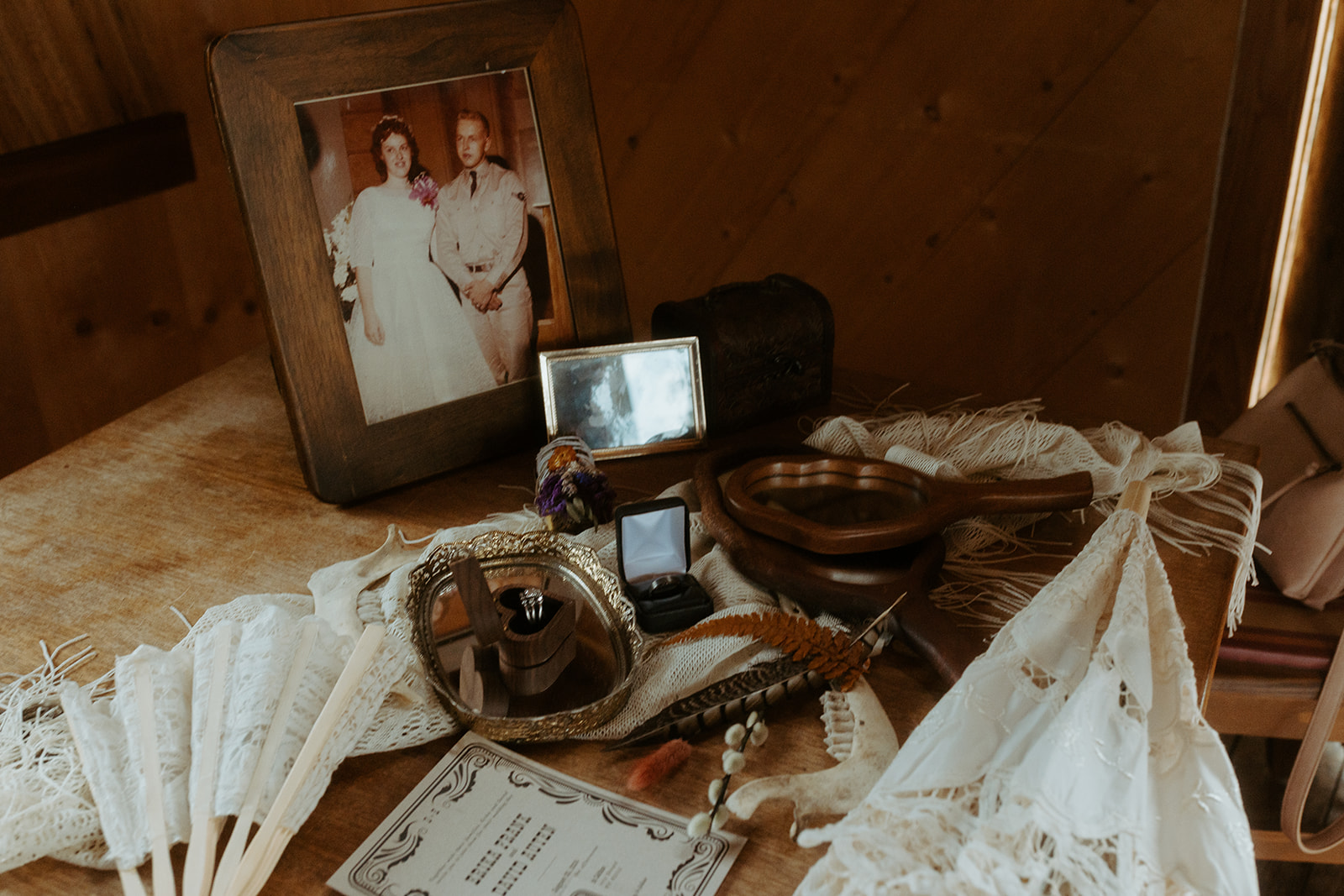 A table holding various items including lace fans, a framed photo of a couple, decorative bowls, a certificate, and small figurines.