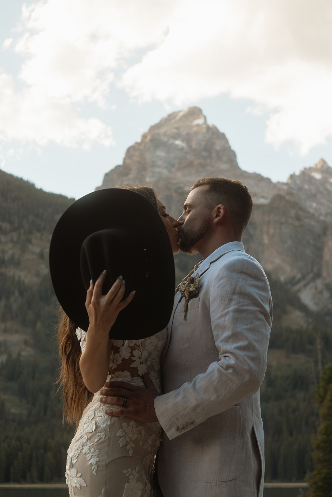 A man and woman in wedding dress standing on a rock by a lake for a Grand Teton National park taggart lake elopement