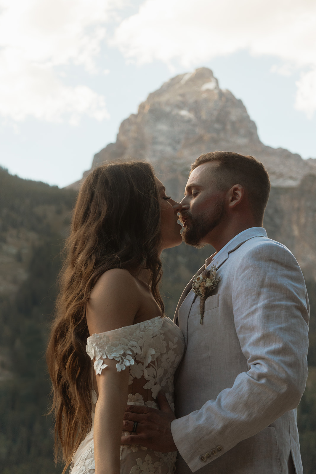 A man and woman in wedding dress standing on a rock by a lake for a Grand Teton National park taggart lake elopement