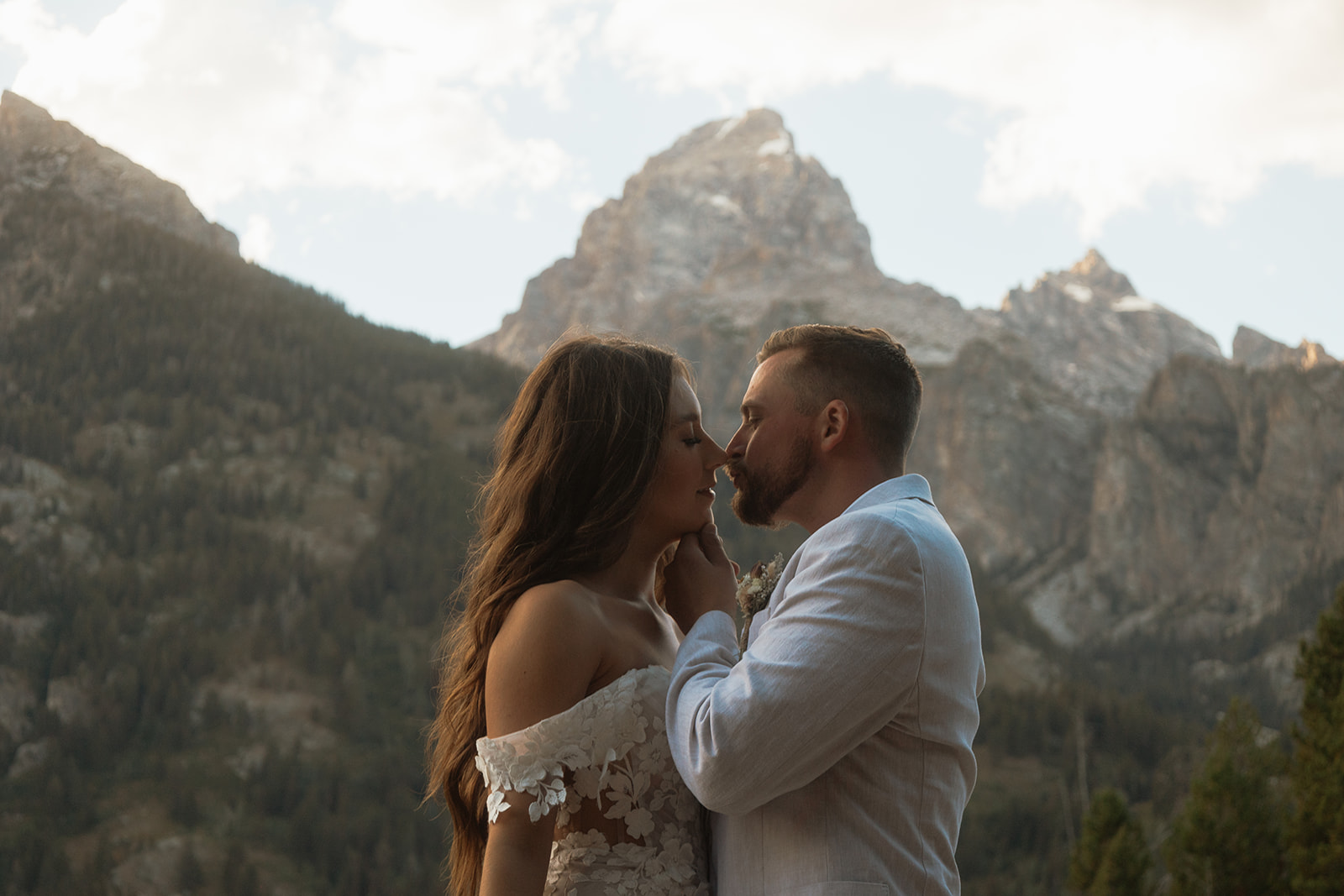 A man and woman in wedding dress standing on a rock by a lake for a Grand Teton National park taggart lake elopement