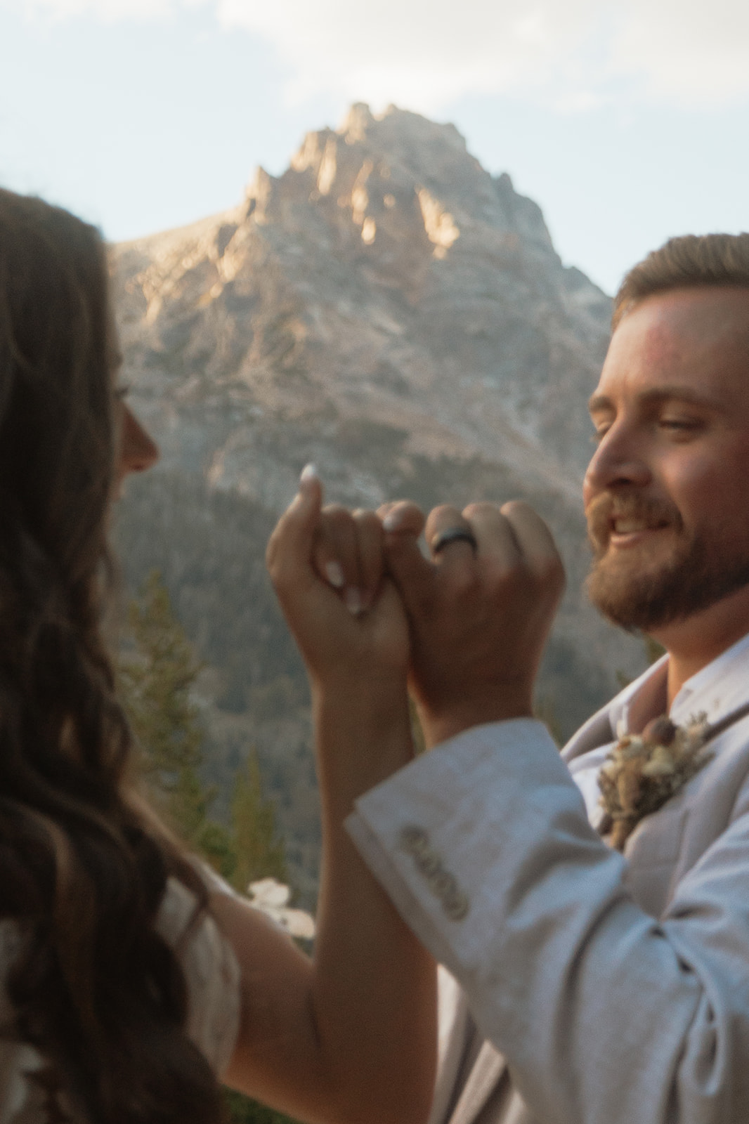 A man and woman in wedding dress standing on a rock by a lake for a Grand Teton National park taggart lake elopement