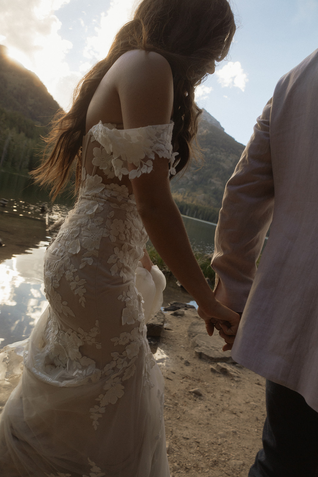 A man and woman in wedding dress standing on a rock by a lake for a taggart lake elopement