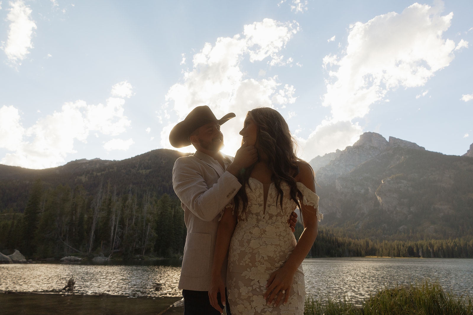 A man and woman in wedding dress standing on a rock by a lake for a Grand Teton National park taggart lake elopement