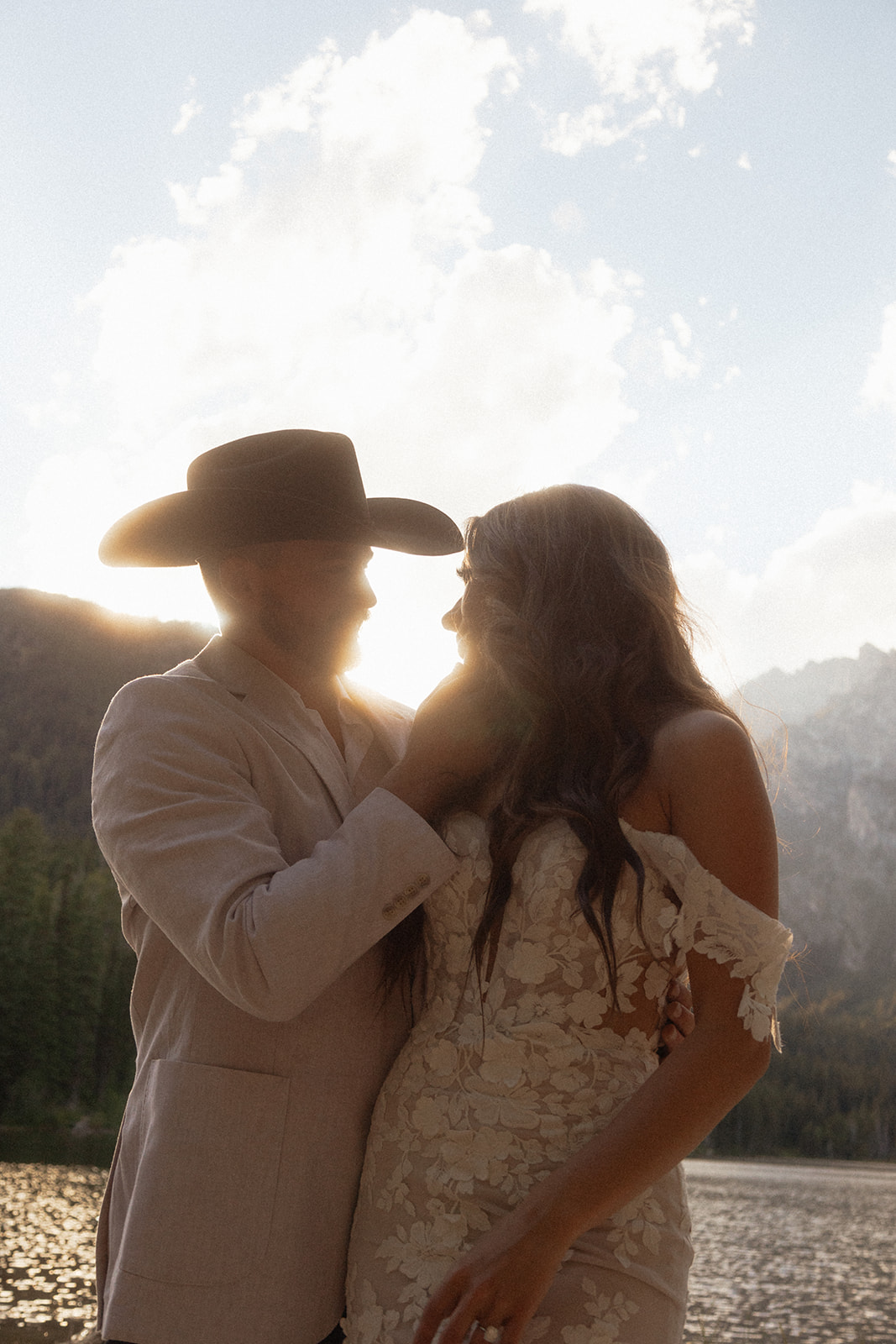 A man and woman in wedding dress standing on a rock by a lake for a Grand Teton National park taggart lake elopement