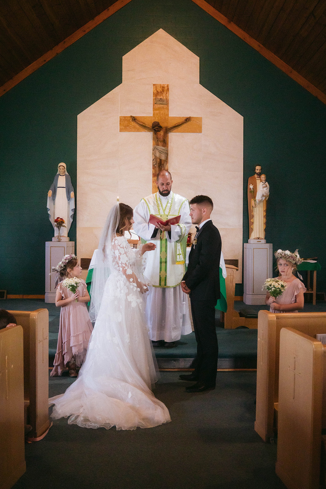 A bride and groom face each other in front of a priest during a ceremony in a church in Gardiner, Montana 