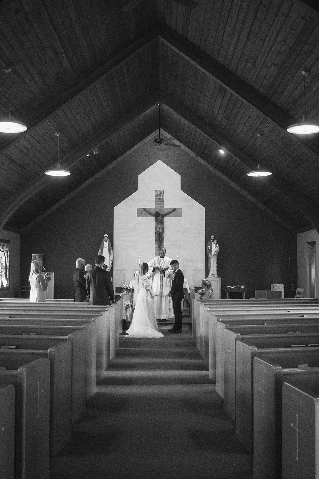 A bride and groom face each other in front of a priest during a ceremony in a church in Gardiner, Montana 