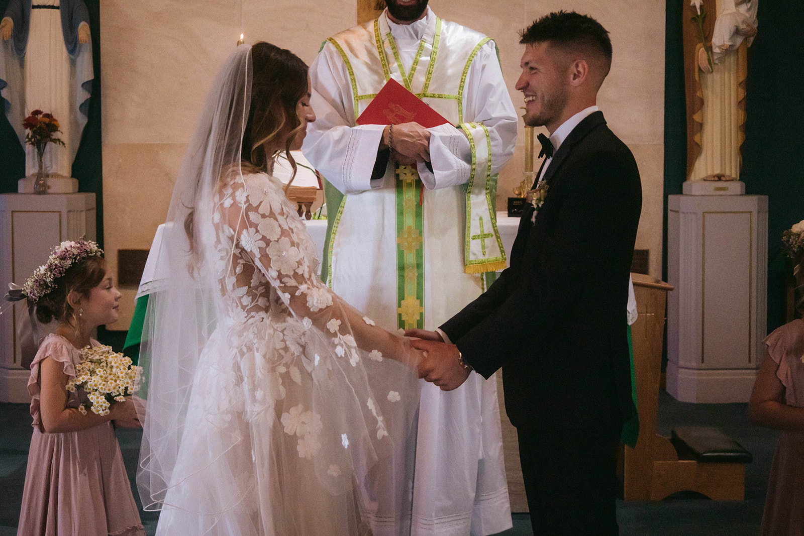 A bride and groom face each other in front of a priest during a ceremony in a church in Gardiner, Montana 