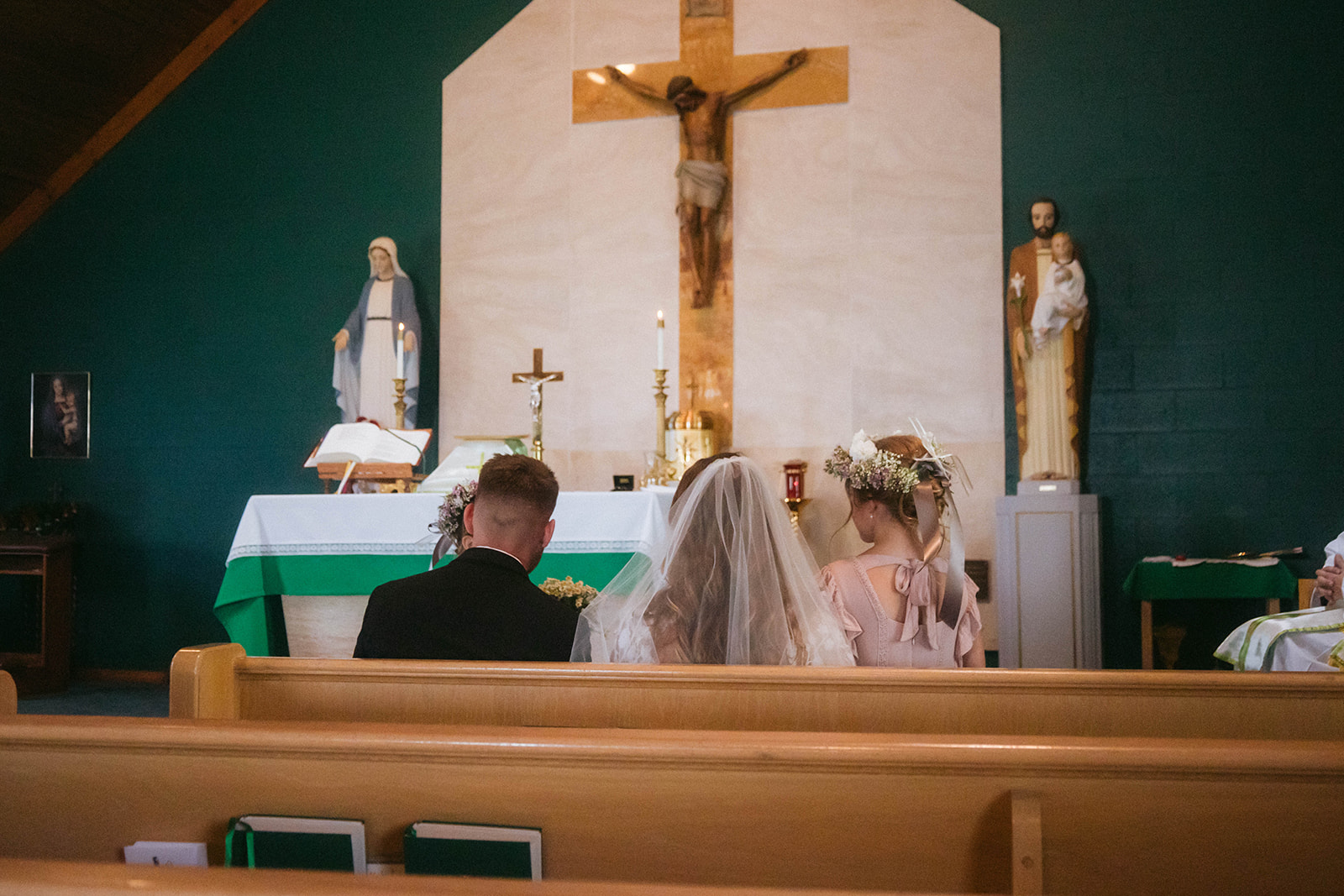 A bride and groom face each other in front of a priest during a ceremony in a church in Gardiner, Montana