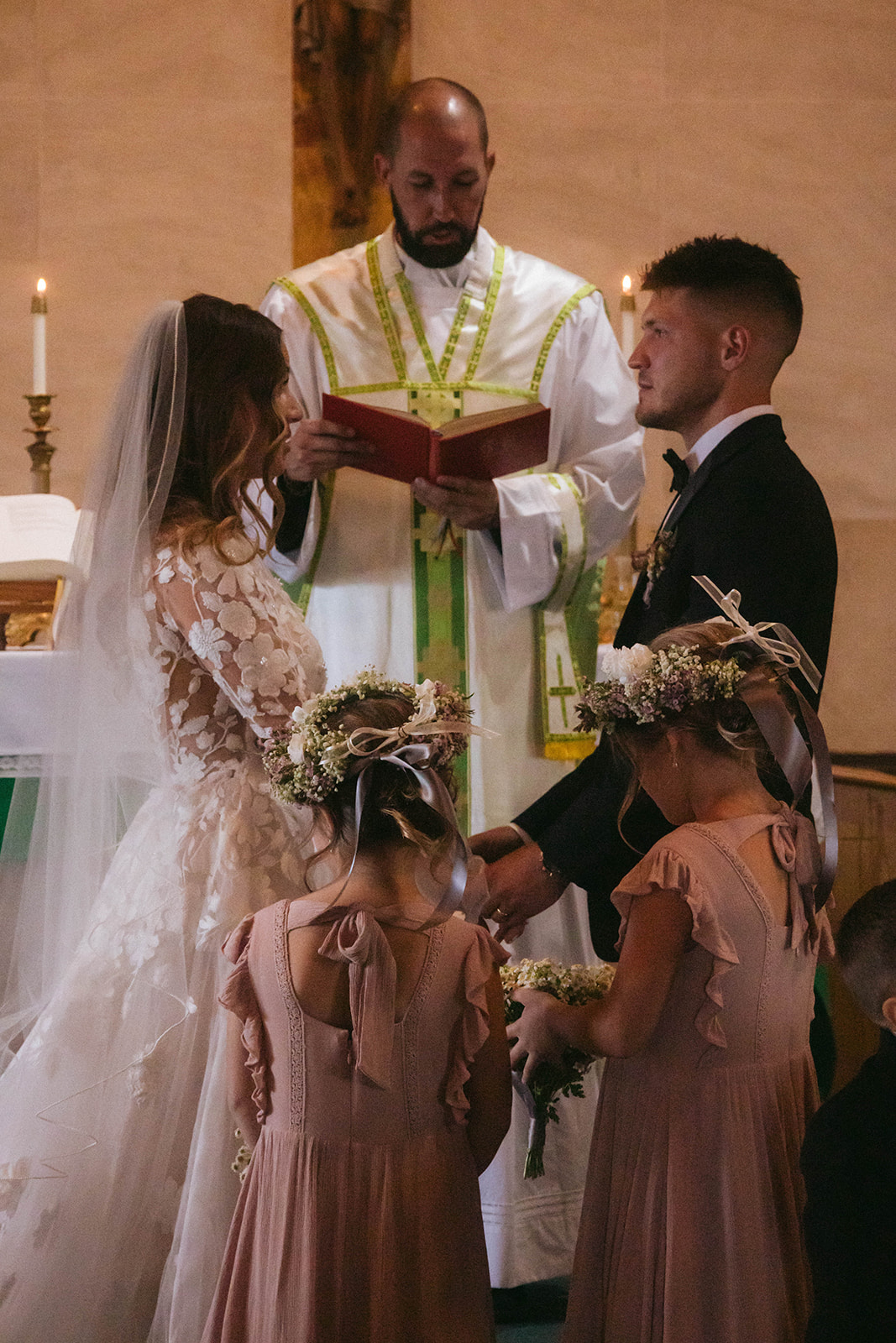 A bride and groom face each other in front of a priest during a ceremony in a church in Gardiner, Montana 