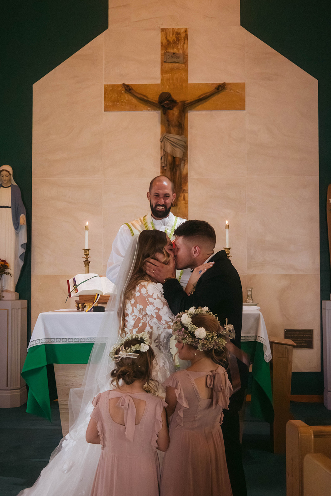 A bride and groom face each other in front of a priest during a ceremony in a church in Gardiner, Montana 